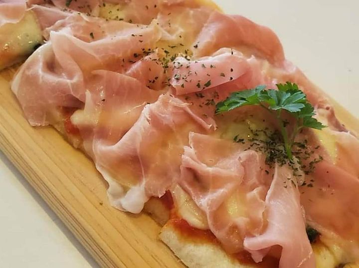 イタリア産生ハムをスライスし、焼きたてのピッツァにたっぷりとのせています。