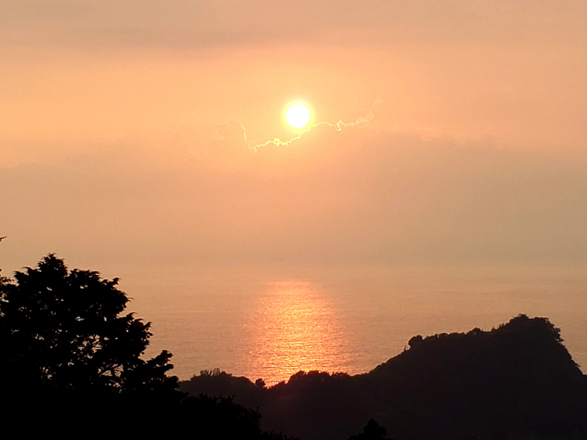 黄昏に染まる空の下　海に夕陽の道が続く