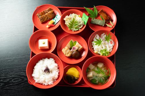 季節の精進料理の本膳。ごまどうふ、精進うなぎ、季節の野菜の天ぷら、生麩の田楽、季節の炊きもの、冷やしうどん、ご飯、味噌汁、香の物が膳に並びます